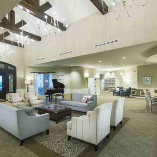 A spacious and modern living room with elegant chandeliers and comfortable seating.