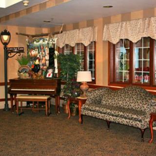 A cozy sitting room featuring a piano, patterned sofa, and warm lighting.