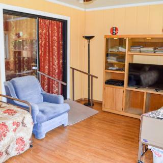 A cozy living room with a blue armchair, wooden bookshelf, and television on a hardwood floor.