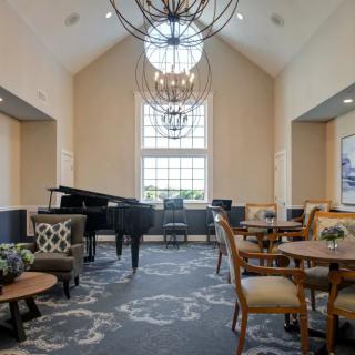 A well-lit lounge area with a grand piano and comfortable seating arrangements.