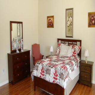 A neatly arranged bedroom with wooden furniture and decorative artwork on the walls.