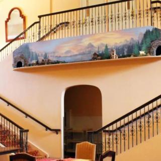 A beautifully decorated interior featuring a split staircase with a scenic mural along the upper wall.