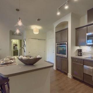 A modern kitchen featuring wooden cabinets, an island counter with pendant lighting, and built-in appliances.