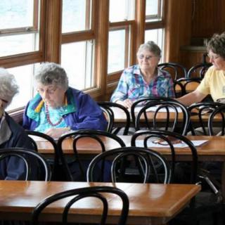 A group of seniors sitting together in a cafe, engaging in conversation.