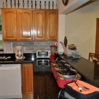 A neatly organized kitchen featuring wooden cabinets, a black countertop, and various appliances including a coffee maker and toaster oven.