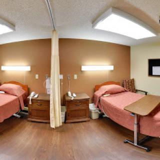 A panoramic view of a hospital patient room featuring two beds.