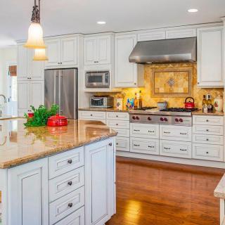 A modern kitchen with white cabinets, stainless steel appliances, and a central island.