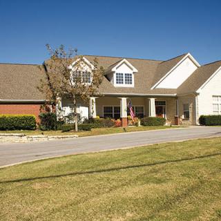A suburban house with a large front lawn and a clear blue sky.