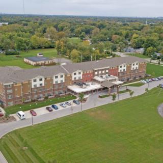 Aerial view of a hotel building surrounded by greenery and parking spaces.