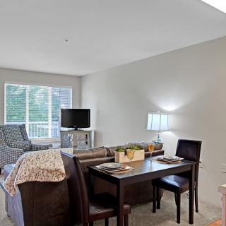 A cozy living and dining area featuring a table, chairs, and a comfortable seating arrangement near a window.