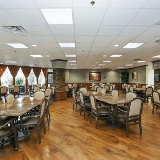 An empty dining area with neatly arranged tables and chairs, featuring a wooden floor and soft lighting.