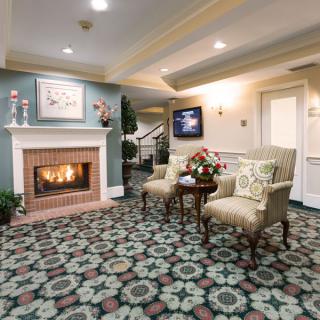 A cozy sitting area with a fireplace, adorned with patterned carpet and elegant chairs.