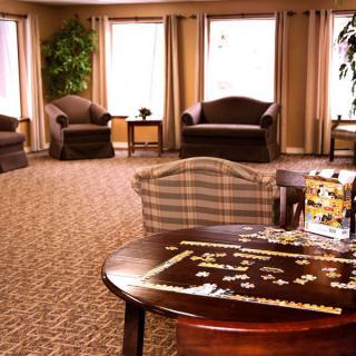 A cozy living room with comfortable seating and a table featuring a partially completed puzzle.