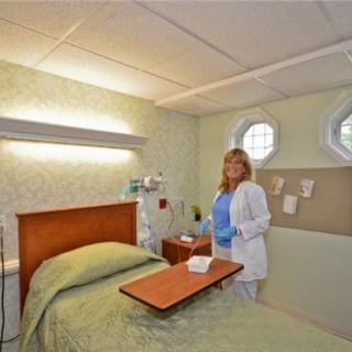 A nurse stands in a hospital room next to a bed.