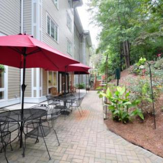 A charming outdoor patio area with tables and red umbrellas beside a landscaped garden path.