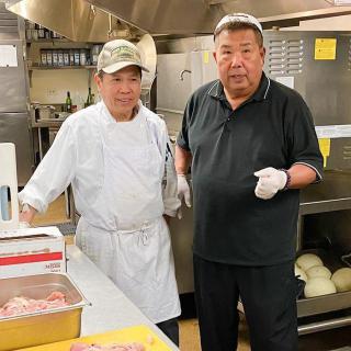 Two chefs in a kitchen preparing food.