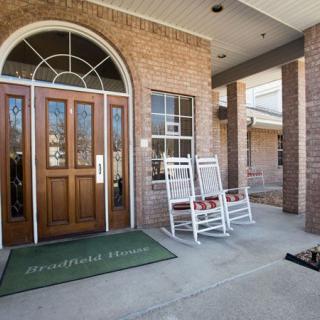 Front entrance of a building with wooden double doors and rocking chairs.