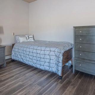 A minimalist bedroom with a single bed, dresser, and nightstand.