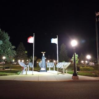 A serene night view of a park featuring illuminated flags and a monument.