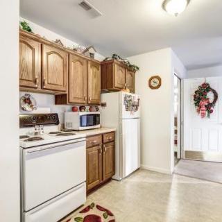A cozy kitchen with wooden cabinets, featuring a stove, microwave, and refrigerator.