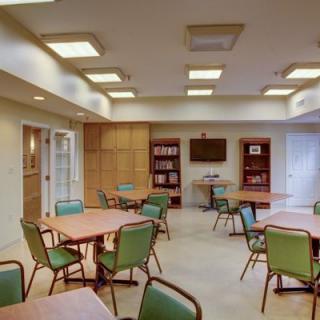 A modern conference room with tables, chairs, bookshelves, and a television.