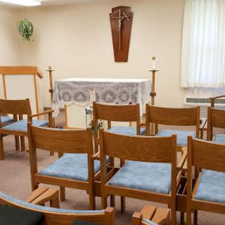 A serene chapel interior with wooden chairs arranged for a gathering.