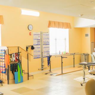 A well-lit physical therapy room equipped with parallel bars and various rehabilitation tools.