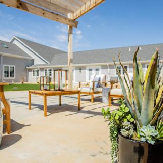 A sunny outdoor patio with modern furniture and potted plants.