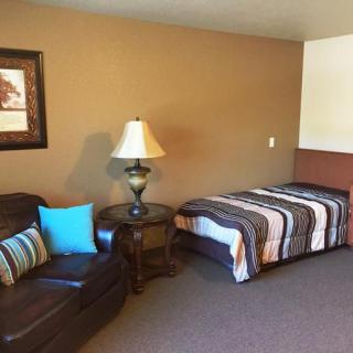 A cozy bedroom with a single bed, sofa, and decorative lamp.