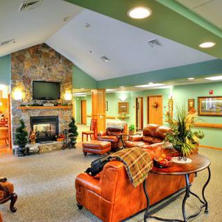 A cozy living room with leather furniture, a stone fireplace, and a mounted television.