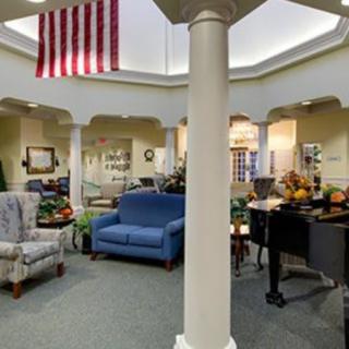 A cozy living space featuring a piano, various seating options, and an American flag hanging from the ceiling.