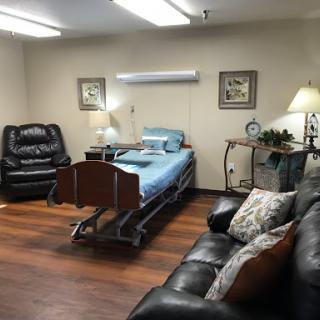 A well-furnished hospital room featuring a bed, comfortable seating, and soft lighting.