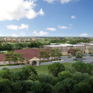 An aerial view of a large building complex surrounded by lush greenery and under a partly cloudy sky.