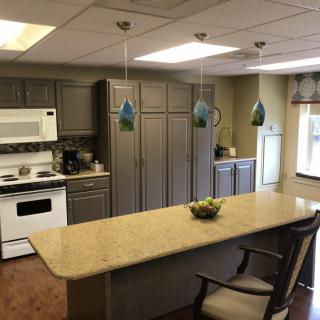 A modern kitchen with gray cabinets, a large island, and decorative pendant lighting.