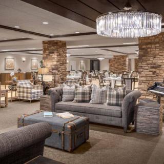 A modern lounge area featuring stylish furniture, a crystal chandelier, and brick columns.