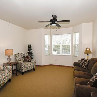 A cozy living room with comfortable seating, a ceiling fan, and soft lighting.