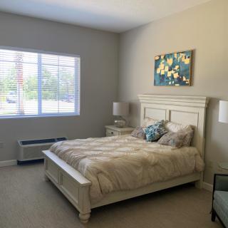 A cozy bedroom with a comfortable bed, soft lighting, and a window with blinds.