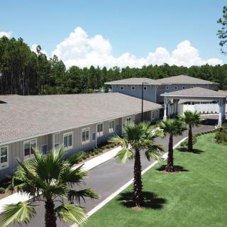 A residential building surrounded by palm trees and a clear blue sky.
