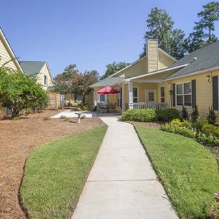 A walkway leading through a well-maintained residential yard with houses and landscaping.