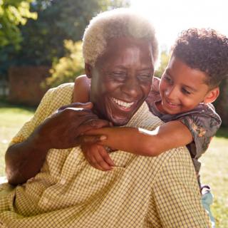 A joyful grandparent and child enjoying a sunny day outdoors.