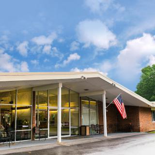 A modern building featuring large glass windows, complemented by an American flag, set against a cloudy sky.