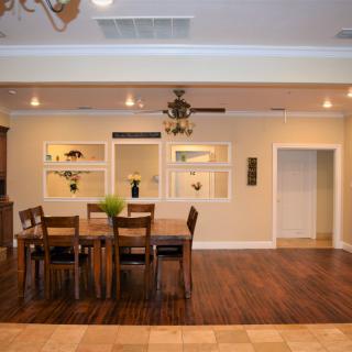 A modern dining room with a wooden table and chairs, featuring wood flooring and stylish decor.