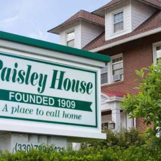 A sign reading 'Paisley House' in front of a residential building with greenery.