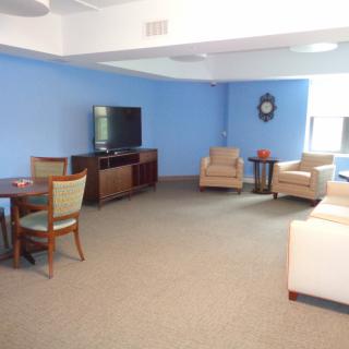 A cozy living room with blue walls, featuring a TV, sofa, chairs, and a table.