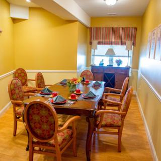 A warmly decorated dining room featuring a wooden table set for a meal, surrounded by comfortable chairs and bright yellow walls.