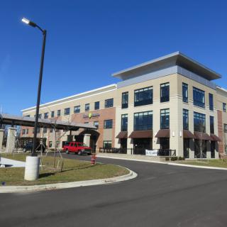 A modern office building with large windows and a parking area.