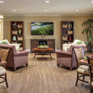A cozy living room with comfortable seating, a wall-mounted television, and decorative shelves.