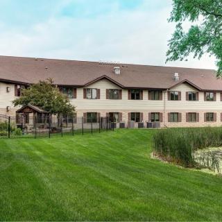 A two-story residential building with a well-maintained lawn and surrounding greenery.