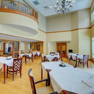 An elegant and spacious dining room with neatly arranged tables and chairs under a chandelier.