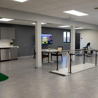A spacious physical therapy and rehabilitation center with exercise equipment and parallel bars for patient support.